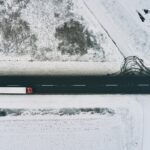 Aerial view of semi-trailer truck driving down the road in winter through countryside, top view drone pov