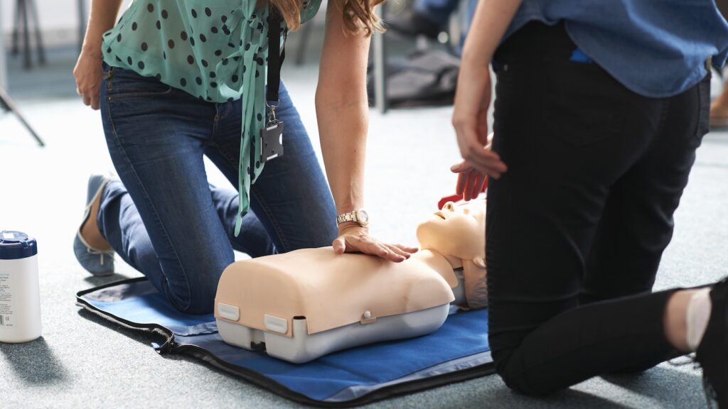 student performing CPR on mannequin in class