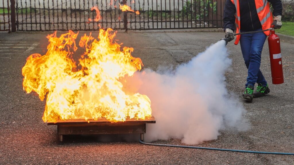 Corporate fire safety exercise. Man using a fire extinguisher.