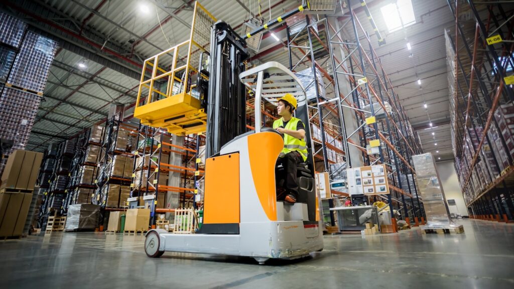 Forklift operator during work in large warehouse