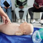 Close-up of female instructor using mannequin on floor to teach cardiopulmonary resuscitation at training class