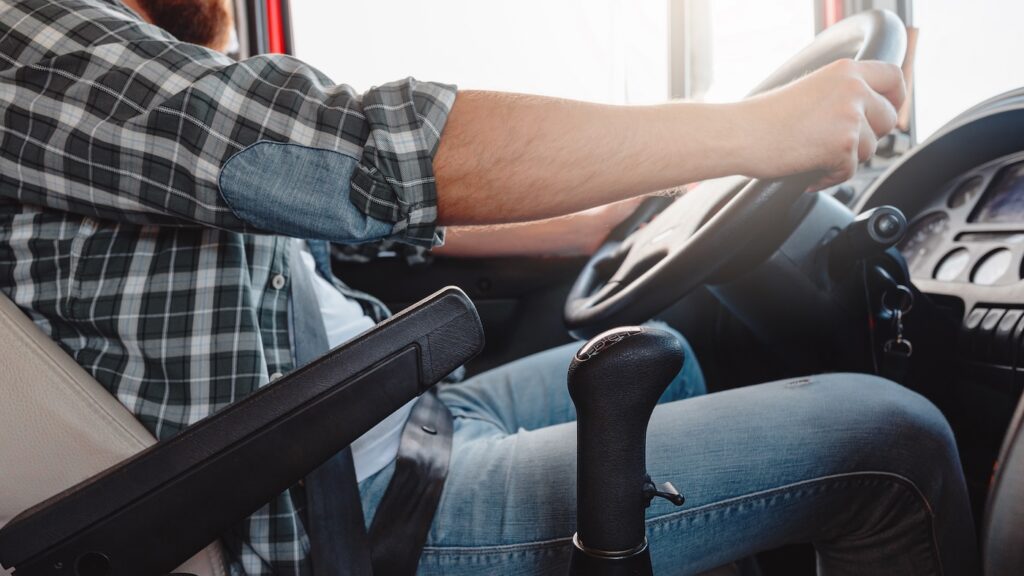 Male truck driver driving truck. Hands of wheel.